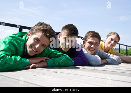 Tre ragazzi e un ragazzo che giace accanto all'altra sul pavimento, di relax al sole Foto Stock