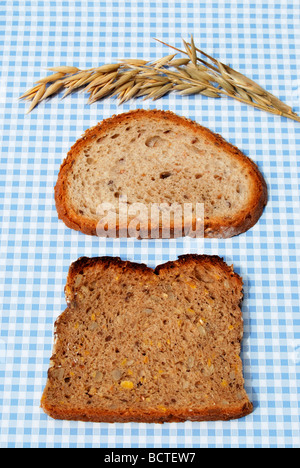 Due fette di pane sul blu e tovaglia bianca, con avena Foto Stock