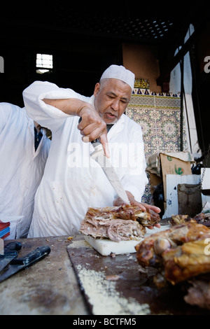 L'uomo vendita di deliziosi piatti a base di carne di agnello in un vicolo del mercato (souk o souq) nella città vecchia (a) Medina di Marrakech, Marocco. Foto Stock