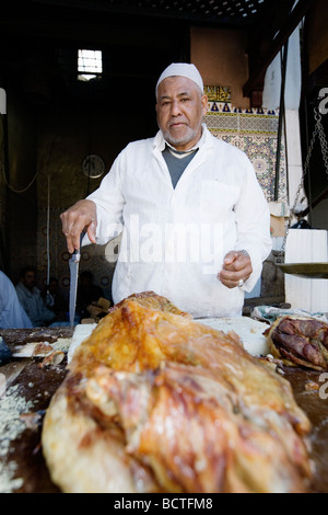 L'uomo vendita di deliziosi piatti a base di carne di agnello in un vicolo del mercato (souk o souq) nella città vecchia (a) Medina di Marrakech, Marocco. Foto Stock