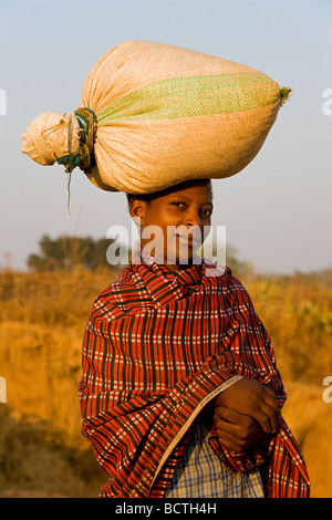 Donna indigena che porta un sacco di pesanti sul suo capo, Zambia, Africa Foto Stock