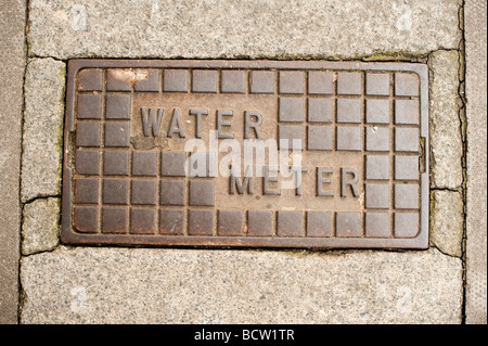 Misuratore di acqua chiusino sul marciapiede in strada Foto Stock