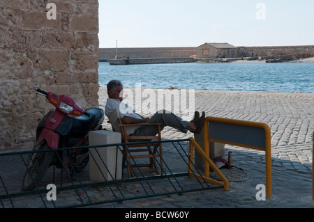 Uomo di relax con i suoi piedi fino al Porto di Chania, Creta, Grecia. Foto Stock