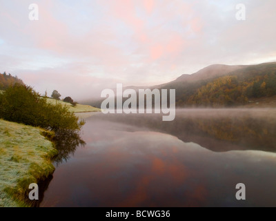 Foschia sopra l'acqua durante il Sunrise al serbatoio Ladybower riflessa nell'acqua, DERBYSHIRE REGNO UNITO Inghilterra Foto Stock