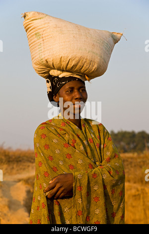 Donna indigena che porta un sacco di pesanti sul suo capo, Zambia, Africa Foto Stock
