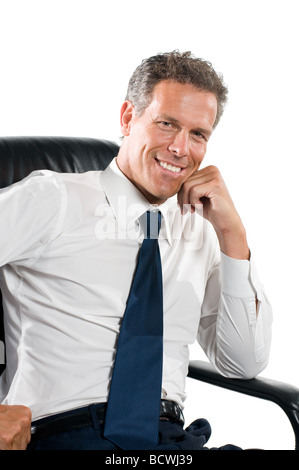 Sorridere soddisfatto imprenditore guardando la telecamera sedere nella sua sedia isolati su sfondo bianco Foto Stock