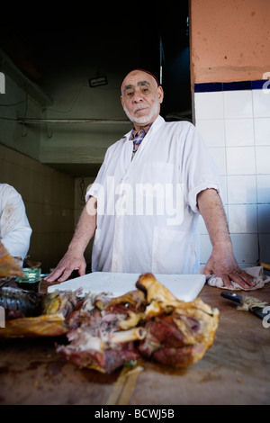 L'uomo vendita di deliziosi piatti a base di carne di agnello in un vicolo del mercato (souk o souq) nella città vecchia (a) Medina di Marrakech, Marocco. Foto Stock