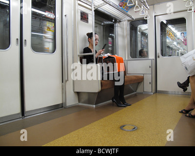 Un " commuter " utilizzando un telefono cellulare in una stazione della metropolitana treno metro a Tokyo Giappone Foto Stock