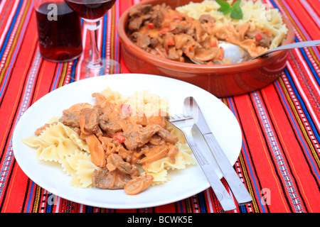 Una cena a base di carne di manzo stroganoff con pasta e vino Foto Stock