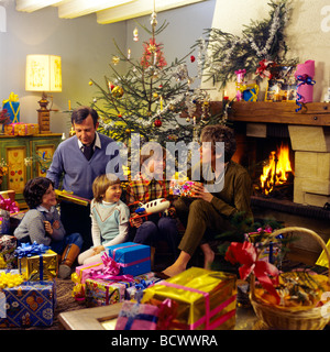 Signor giovane dando i regali di Natale per i bambini al di sotto della struttura ad albero Foto Stock