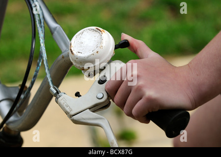 Childs pollice squilla una campana di ciclo Foto Stock