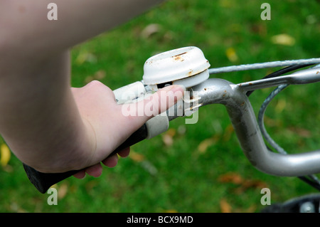 Childs pollice squilla una campana di ciclo Foto Stock