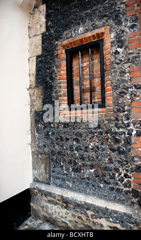Vecchia finestra con bar in mattoni e pareti in pietra. Foto Stock
