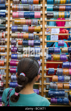 Ragazza giovane guardando i braccialetti colorati stand in Mela evento asiatico a Manchester REGNO UNITO Foto Stock