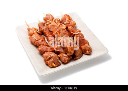 Spiedini di carne su una piastra isolata su bianco Foto Stock