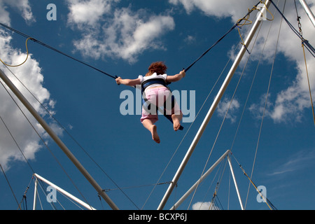 Un giovane dai capelli rossi ragazza gode di un trampolino ride sotto i cieli blu al quinto Colchester Festival militare in Essex, Inghilterra Foto Stock