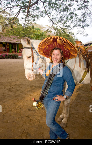 Tequila Bandita, ragazza pone con cavallo e colpi di tequila a tequila fabbrica a nord di Mazatlan, Messico. Foto Stock