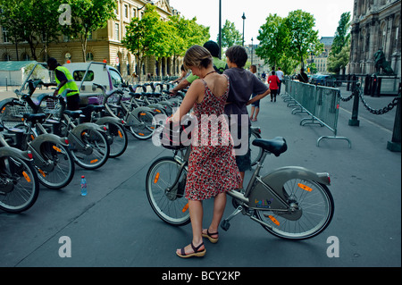 Parigi Francia, Donna francese in abito, posteriore, uso gratuito a noleggio, biciclette pubbliche, Velib, bicicletta, persone per le strade di Parigi Foto Stock