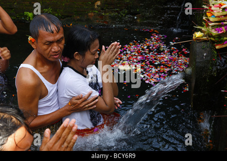 L uomo e la donna nel corso di una cerimonia presso la fonte sacra, Tirta Empul a Tampak Siring nella luce del mattino, Bali, Repubblica di Indonesia, Foto Stock