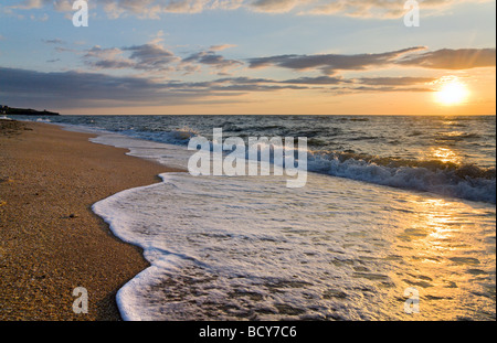 Tramonto sul mare surf grande onda rottura sul litorale sabbioso Foto Stock