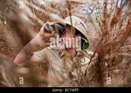 L uomo nella giungla vestito con il binocolo Foto Stock
