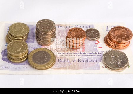 British monete di varie denominazioni sono stabiliti e impilati nella parte superiore di una ventina di pound nota. Foto Stock