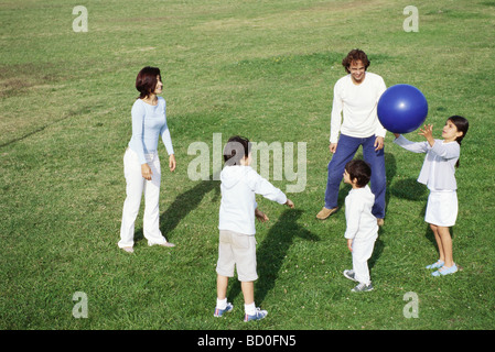 La famiglia gioca con la palla nel campo erboso Foto Stock