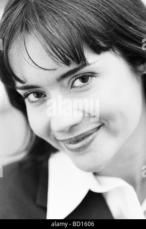 Giovane donna sorridente modestamente in telecamera, ritratto Foto Stock