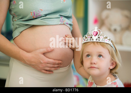 Bambina toccante della madre pancia in gravidanza Foto Stock