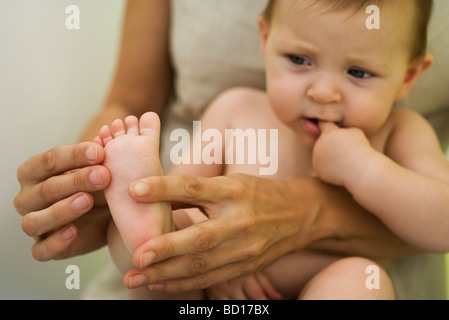 La madre del bambino di contenimento sul giro, giocando con il bambino il piede, ritagliato Foto Stock