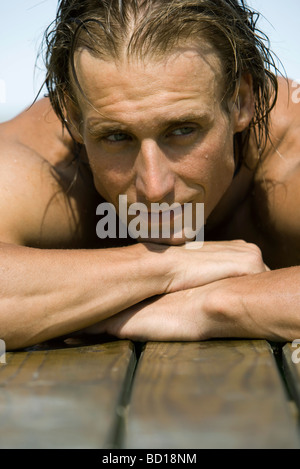 Uomo appoggiato la testa sulle braccia sul lato della piscina Foto Stock