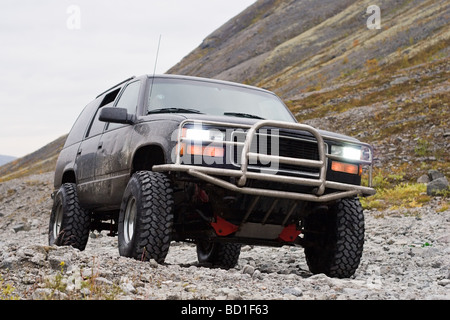 Auto off road con accensione fari anteriori su sfondo di montagna Foto Stock