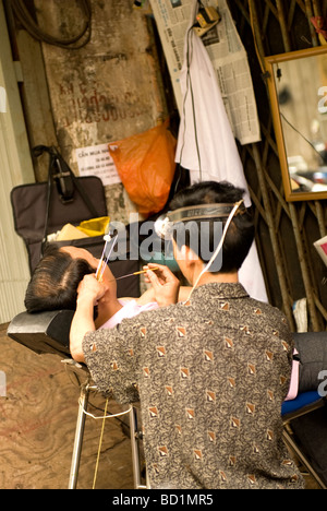 Aria aperta barbiere, barbiere è cliente di pulizia dell' orecchio, il vecchio quartiere di Hanoi ,il Vietnam . Foto Stock