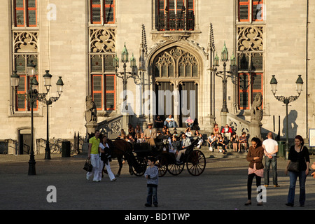 Carrello con i turisti sul Grote Markt square con Provinciaal Hof corte provinciale edificio in Bruges Belgio Foto Stock