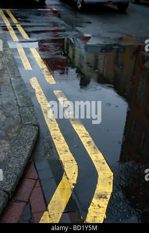 Doppio giallo linee su un lato umido street a Manchester Foto Stock