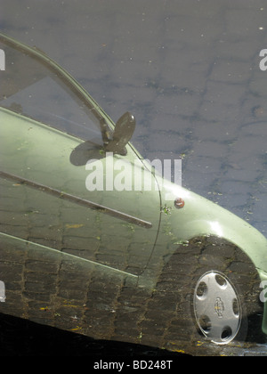 Uno verde auto parcheggiata la riflessione sulla strada allagata Foto Stock