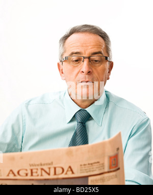 Manager con gli occhiali lettura di un quotidiano modo concentrato Foto Stock