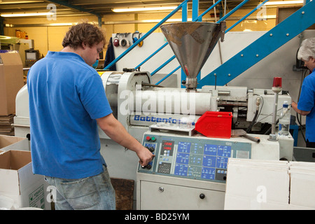 L'uomo opera macchina di stampaggio ad iniezione per la produzione di parti in plastica Foto Stock
