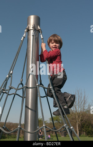 giovane ragazzo che sale in cima a una piramide con telaio rotante per arrampicata, di tre anni Foto Stock