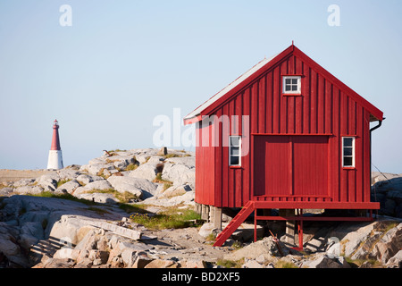 Il Boathouse rosso sull'isola Grip in Norvegia il faro in backround Foto Stock