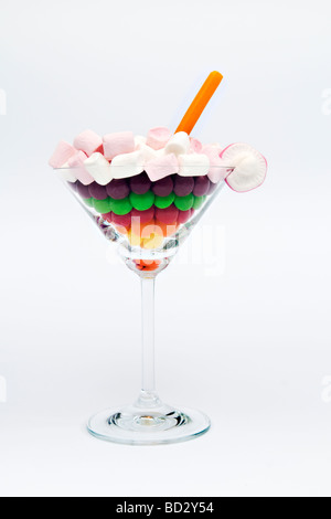 Ancora vita scatti artistici di miscela di diversi dolci nel bicchiere da cocktail contro uno sfondo bianco Foto Stock