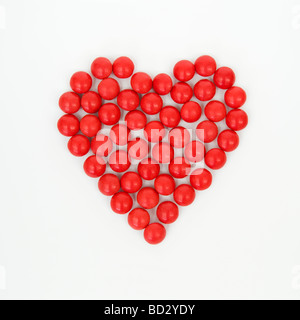 Ancora vita artistica di shot dolciumi rossa insieme a forma di cuore prese contro uno sfondo bianco come formato quadrato Foto Stock