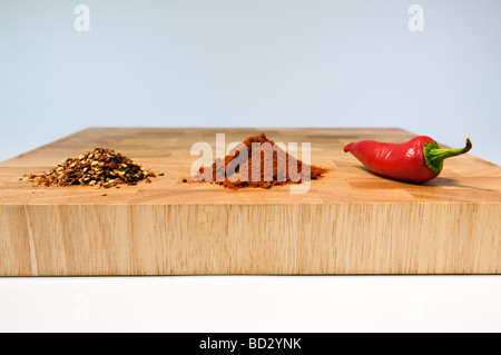 Selezione dei tipi di peperoncini secchi, polverizzato e fresche, sul tagliere di legno Foto Stock