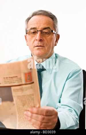 Manager con gli occhiali lettura di un quotidiano modo concentrato Foto Stock