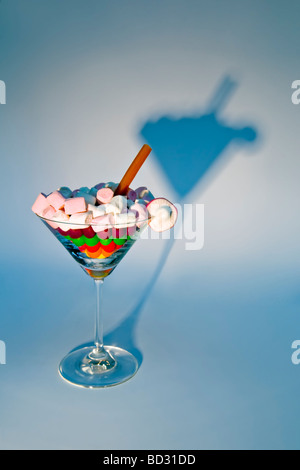 Ancora vita scatti artistici di miscela di diversi dolci nel bicchiere da cocktail contro uno sfondo bianco con ombra Foto Stock