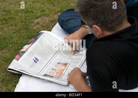 Lettura di un quotidiano sull'erba a Ealing Jazz Festival 2009. Foto Stock