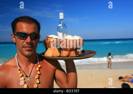 Il Barman con noce di cocco cocktails Rum su Playa Megano, Playas del Este, Avana, Cuba. Foto CUBA1230 Copyright Christopher P Baker Foto Stock
