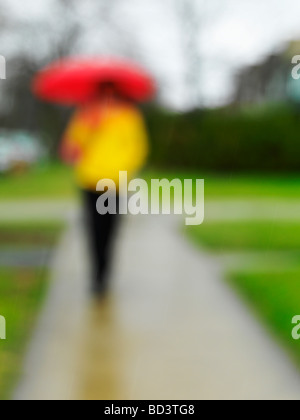 Donna in abiti colorati con ombrello in caso di pioggia Foto Stock