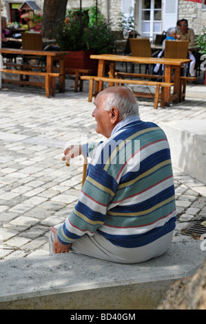 Anziani pensionati vecchio seduto rilassante guardando osservando in appoggio sul bastone in ombra sulla luminosa giornata di sole in Francia Foto Stock