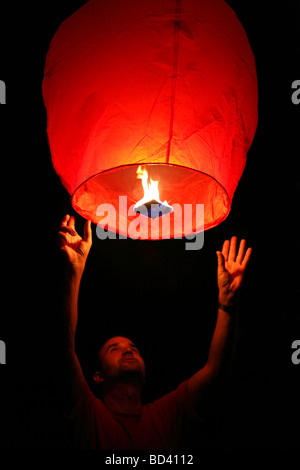 L'uomo lanciando una lanterna di sky nel cielo notturno Foto Stock